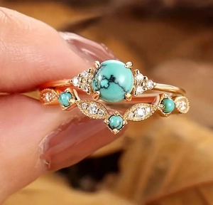 Detail of bohemian gold rings set with turquoise stone and white cubic zirconia