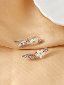 Macro detail of silver flower crawler earrings with pink zircons on orange silk
