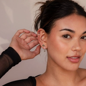 Close-up of vintage French green stone stud and silver earring set on model ear