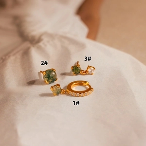 Macro shot of three vintage French moss agate gold earrings on white fabric texture