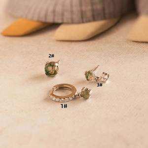 Detail of silver earrings set with natural green moss agate and zircon stones
