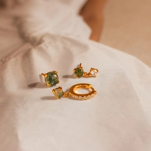 Detail view of gold earrings set featuring green sea grass stone and clear zircons
