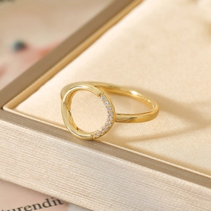 Close-up of golden hollow ring featuring micro-paved zircons on a satin background