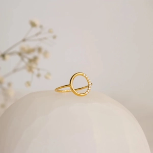 Detail of minimalist gold hollow round ring with side micro-diamond accents on a prop