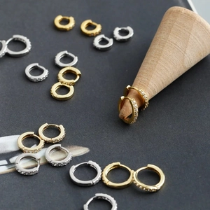 Macro detail of minimalist gold and silver huggie earrings with cubic zirconia inlay