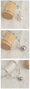 Detail van zilveren kralenketting met witte en grijze parelhangers en zirkoonaccent