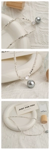 Detail van zilveren kralenketting met een grijze parelhanger en sprankelende zirkoonsteen