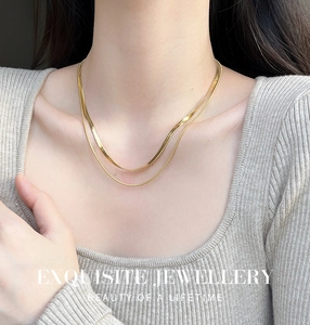 Gros plan détaillé du collier double chaîne serpent dorée porté sur la clavicule