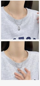 Detailed view of hollow teardrop pendant on snake chain worn over a grey sweatshirt