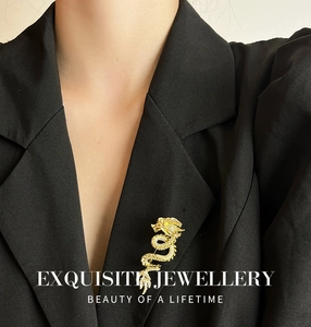 Detailed close-up of a gold Chinese dragon brooch with white zircons on a black blazer