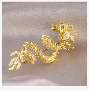 Macro detail of golden dragon brooch with shimmering white zircons on silk background