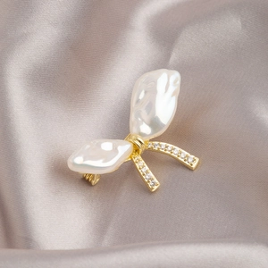 Elegante spilla a fiocco con perle barocche, dettagli dorati e zirconi incastonati