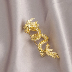 Exquisite gold Chinese dragon brooch with shimmering white crystals on grey silk fabric