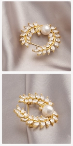 Detail van de korenvleugspeld met marquise-zirkonia, parel en goudkleurige legering