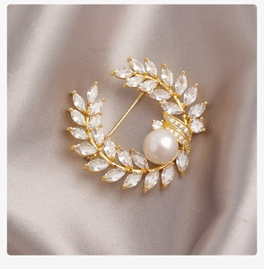 Detail van een gouden tarwekrans broche met marquise kristallen en een parel