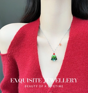 Detail van kerstboom ketting met groene kristallen gedragen op een rode gebreide trui