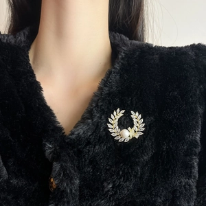 Elegante gouden tarweblad broche met zirkonen en parel op een zwarte bontjas
