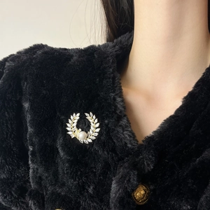 Elegante gouden krans broche met tarwe-oren, zirkonia en een witte parel op zwart bont