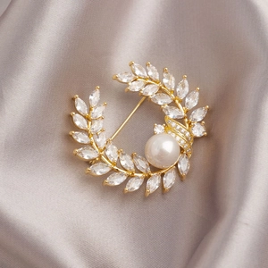 Elegante gouden tarwe-oor broche met sprankelende kristallen en een grote witte parel