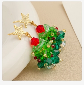 Detailopname van kerstboom oorbellen met gekleurde kralen en gouden ster accenten