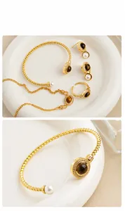 Detailed macro view of gold-tone twisted bangle featuring tiger eye stone and pearl accents
