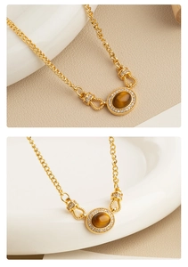 Detail of gold necklace featuring oval tiger eye pendant with white diamond border