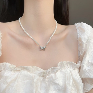 Elegant French vintage bow pendant necklace with pearls on a female model collarbone