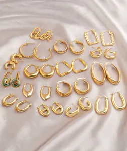 Flat lay of multiple minimalist gold geometric oval earrings on a grey silk fabric