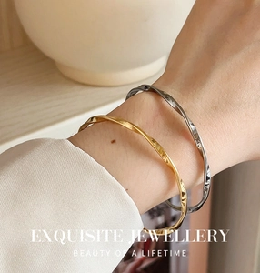Close-up of twisted Mobius titanium steel bangles in gold and silver finish