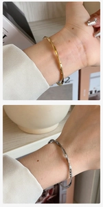Detail of twisted Mobius titanium steel cuff bracelets in polished gold and silver finishes