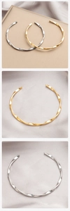 Detailed view of polished Mobius twisted open bangles in gold and silver finishes