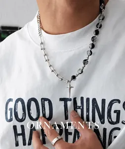 Dettaglio della collana con ciondolo a croce e perle a stella indossata da un modello