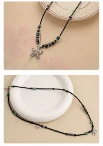 Detailopname van retro ketting met groene kralen en een zilveren vlinder hanger sieraad