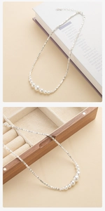 Detail van zilverkleurige nuggetketting met gegradueerde witte parels en sluiting