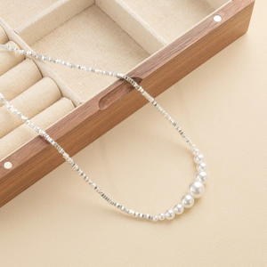 Elegante zilveren kralenketting met zeven gegradueerde parels op een houten doos