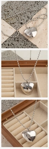 Detalle de un colgante de corazón hueco pulido en plata con cadena de bolas sobre piedra