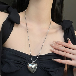 Collar con colgante de corazón de plata pulida y cadena de cuentas en una modelo