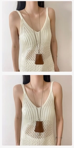 Dettaglio di una collana clochette in pelle marrone con cuciture bianche su abito