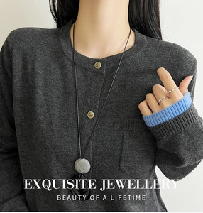 Gros plan d'un collier à long pendentif avec anneaux en marbre gris et noir sur un mannequin