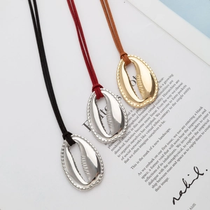 Collana con ciondolo a conchiglia metallica e cordini colorati su sfondo di moda