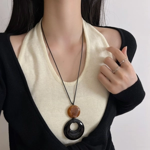 Collier long minimaliste avec anneau noir et perle en résine ambrée sur cordon