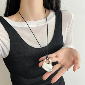 Minimalistische zilveren hartjesketting met zwart koord gedragen door een model