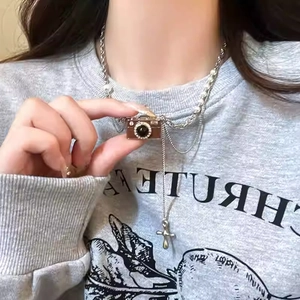 Collana con ciondolo fotocamera retrò con perle e dettagli di nappe su una felpa