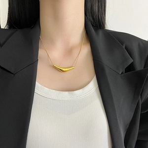 Elegant gold-tone irregular curved bar necklace on a woman wearing a black blazer