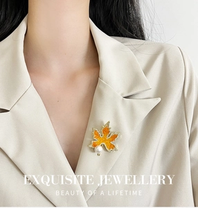 Détail d'une broche feuille d'érable avec zircon et perle sur le revers d'un blazer