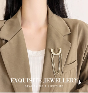Exquisito broche de borla con circonita bañada en oro en blazer beige con cristales
