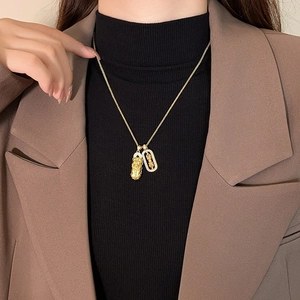 Golden PiXiu pendant necklace with diamond-encrusted frame on a brown blazer background