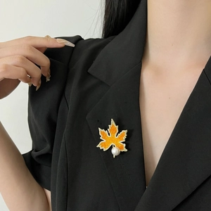 Broche élégante feuille d'érable orange scintillante avec perle sur un blazer noir