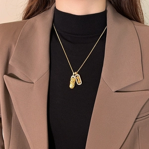 Golden Pixiu and Good Fortune pendant necklace worn on elegant black and brown outfit