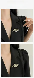 Détail d'une broche épi de blé dorée avec strass blancs sur le revers d'un costume noir